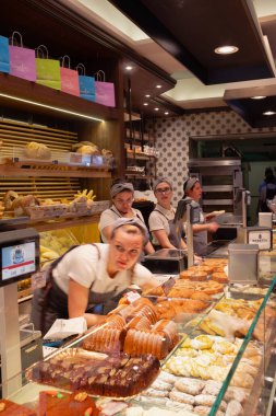 Como, İtalya - 17.12.2025: Çok güzel dekore edilmiş İtalyan pastanesi, tezgahın arkasında müşterilere hizmet veren kadın işçiler. Büyük bir İtalyan hamur işi, ekmek, pizza ve diğer yiyecekler..