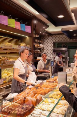 Como, İtalya - 17.12.2025: Çok güzel dekore edilmiş İtalyan pastanesi, tezgahın arkasında müşterilere hizmet veren kadın işçiler. Büyük bir İtalyan hamur işi, ekmek, pizza ve diğer yiyecekler..