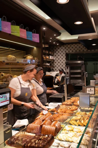 Como, İtalya - 17.12.2025: Çok güzel dekore edilmiş İtalyan pastanesi, tezgahın arkasında müşterilere hizmet veren kadın işçiler. Büyük bir İtalyan hamur işi, ekmek, pizza ve diğer yiyecekler..