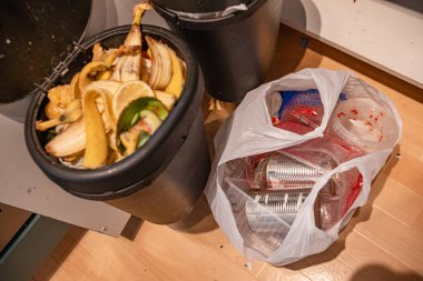 Özgün olarak sıralanmış ev atığı fotoğrafı: organik artıklarla dolu bir gübre kutusu ve geri dönüşümlü plastik torba (teneke, plastik). Evdeki sürdürülebilirlik, atık yönetimi ve yeşil yaşam alışkanlıklarını vurgular.