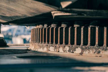 Ağır yük taşıyan bir vinç üzerinde dönen halkanın (döner tabaka taşıyıcısı) detaylı bir düşük açılı çekimi. Açık hava ortamında sağlam mühendislik, endüstriyel mekanik, pas dokusu, bakım gereksinimleri ve ağır makineleri vurgular.