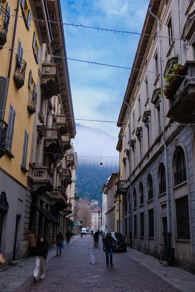 İtalya, Como - 12 / 15 / 2025: Geleneksel mimarisi ve bulutlarla kaplı dağların manzarası ile İtalya 'nın Como kentinin güzel sokakları.