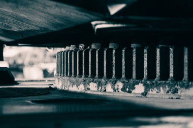 Ağır yük taşıyan bir vinç üzerinde dönen halkanın (döner tabaka taşıyıcısı) detaylı bir düşük açılı çekimi. Açık hava ortamında sağlam mühendislik, endüstriyel mekanik, pas dokusu, bakım gereksinimleri ve ağır makineleri vurgular.