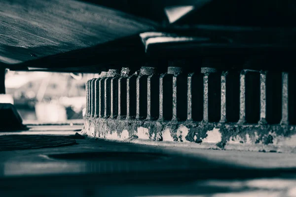 Ağır yük taşıyan bir vinç üzerinde dönen halkanın (döner tabaka taşıyıcısı) detaylı bir düşük açılı çekimi. Açık hava ortamında sağlam mühendislik, endüstriyel mekanik, pas dokusu, bakım gereksinimleri ve ağır makineleri vurgular.