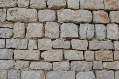 Üst üste dizilmiş taş duvarın yüksek çözünürlüklü yakın çekimi kaba, doğal dokuları, düzensiz şekilleri ve arka plan, mimari tasarım, inşaat malzemeleri ve doku için toprak rengi ideallerini gösterir.