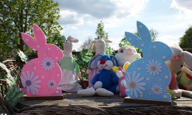 Pastel renkli Paskalya tavşanı kırsal bir bahar bahçesi ortamında peluş tavşan oyuncaklarıyla süslenmiş. Pembe, beyaz ve mavi keçeli tavşanlar neşeli bir bahar ve tatil ortamı yaratır..