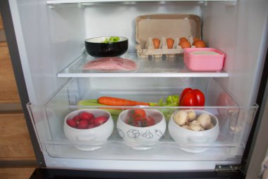 Temiz cam raflarda taze sebzeler, meyve, yumurta, jambon, peynir ve ev yapımı turşular, mantarlı, turplu, domatesli, kerevizli ve havuçlu organize buzdolabı çekmecesi, sağlıklı gıda depolama ve yemek hazırlama konsepti