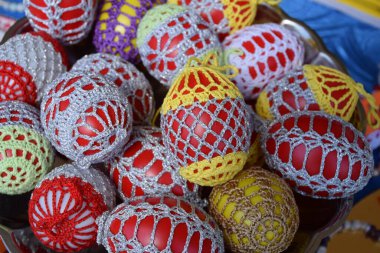 Renkli el yapımı halk örgü örerek küçük sepetlere paskalya yumurtası tıkıştırıyor. Avrupa 'nın bayramlık paskalya pazarında parlak bir masa üzerinde. Dekoratif dantel yumurtalar geleneksel işlemelerle yapılmış ayrıntılı desenler gösteriyor, canlı kırmızı, pembe, mavi, sarı ve pastel renkler.