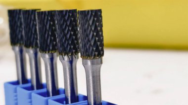 Mavi bir tutacağında elmas şekilli kesikler olan siyah döner alet parçaları. Yakın çekim görünümü.