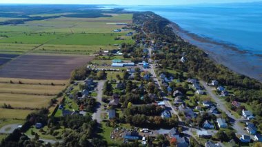 Kıyı köyü Cacouna 'nın panoramik hava manzarası. Evleri, ağaçları ve ana yolu var. St. Lawrence Nehri 'nin kayalık kıyılarıyla çiftlik arazisi arasında sıkışmış. Quebec, Kanada, 2025.