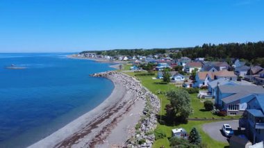 Saint-Ulric-de-Matane kıyı köyünün bulutsuz mavi gökyüzünün altında St. Lawrence nehrinin kıyısında bir uçuş. Quebec, Kanada, 2025.