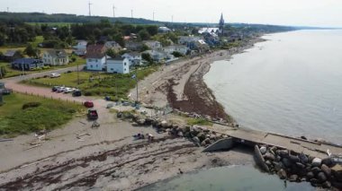 Baie-des-Sables köyündeki küçük turist plajının hava manzarası ve onun renkli evleri rüzgar türbinleri ve St. Lawrence nehri ile çevrili. Gasp Yarımadası, Quebec, Kanada, 2025.