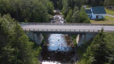 Köprünün altından geçen bir dron tarafından çekilen video, siyah bir kamyonun geçtiği, kayalık bir nehrin, yakınlardaki bir beyaz evin ve yeşil bir ormanın üzerinden alçaktan uçtuğu. Quebec, Kanada.