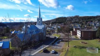 Saint-Jacques-le-Majeur Kilisesi devlet okulunun yakınındaki Causapscal kasabasına bakıyor, ufukta iletişim kulesi olan bir yerleşim yerinin önünde. 2025.