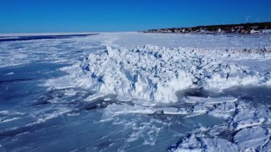 St. Lawrence Nehri 'nin donmuş kıyısındaki Baie-des-Sables kıyı köyünde, mavi gökyüzünün altında rüzgar türbinleri, Gaspe Yarımadası, Quebec, Kanada.