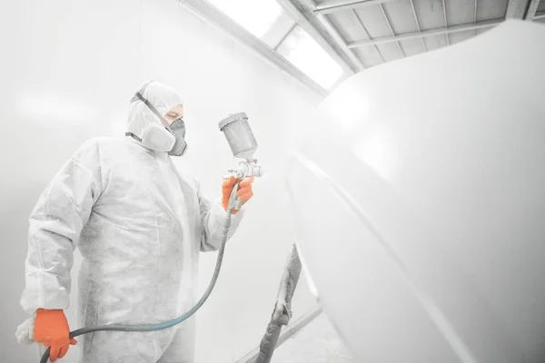 한 노동자가 차에 스프레이 총으로 흰 페인트를 뿌리는 모습. — 스톡 사진