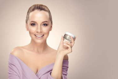 Gülümseyen kadın, bej üzerinde bedava fotokopi alanı olan el kremi kullanıyor..