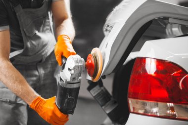 Beyaz arabanın cilalanması, cilalama makinesi ile çalışan işçiler kaportayı kurtarır. Otomobil ayrıntıları.