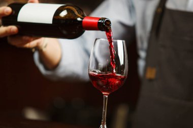 Garson şarap kadehine kırmızı şarap dolduruyor. Sommelier alkollü içecek doldurur.