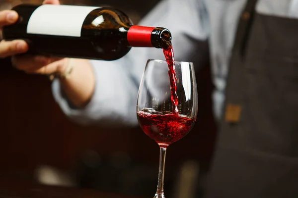 Číšník nalévá červené víno do sklenice na víno. Sommelier nalévá alkoholický nápoj — Stock fotografie
