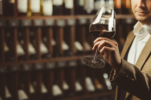 Muž sommelier ochutnávka červeného vína ve sklepě, detailní foto. — Stock fotografie