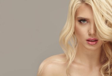 Avrupalı sağlıklı, uzun dalgalı saçlı, izole edilmiş arka planda sarışın bir kadının stüdyo güzelliği.