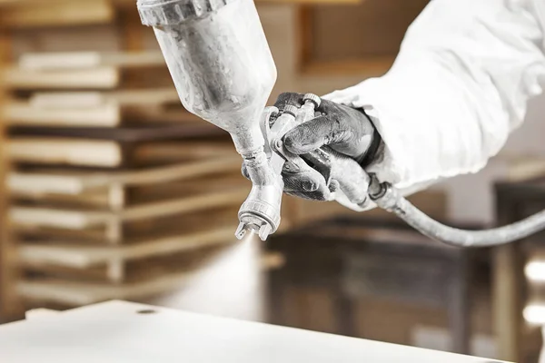 Close-up image of man spraying with gun to the wood. Stock Picture