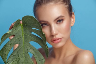 Mavi palmiye yapraklarının yanında çürüyen esmer kadın.