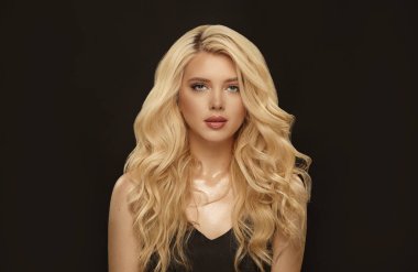 Uzun kıvırcık saçlı sarışın kadın, siyah arka planda güzel bir fotoğraf..