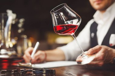 Sommelier, masada kırmızı şarabın tadını anlatan bir form dolduruyor. Alkollü içeceklerin azaltılması.