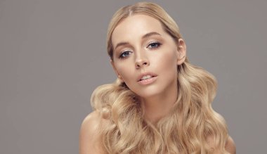 Sarışın, beyaz bir kadının uzun saçları, izole edilmiş açık kahverengi arka planda doğal ciltli kadın yüzünün güzel bir portresi vardır. Saç stili ve saç kesimi, sağlıklı saçlar..