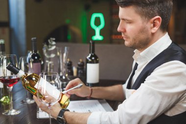 Beyaz şarap karakterlerini inceleyen yetenekli şarap garsonu masadaki günlüğe notlar kaydediyor. Barda oturan mahzen müdürü şişeyi arıyor. Kâhya alkollü içecekler konusunda uzman. Yaklaş, kenar görünüm.