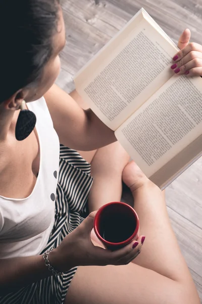 Menina lendo um livro com uma xícara de café — Fotografia de Stock