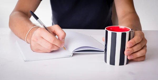 Mãos masculinas escrevendo com uma caneca e livros — Fotografia de Stock