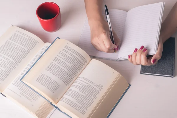 Table with books and coffee and female hands Royalty Free Stock Images