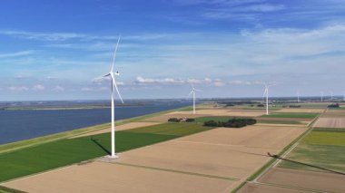 Flevoland Hollanda 'da güneşli bir günde sürdürülebilir enerji üreten rüzgar türbinleri.