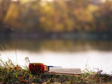 Kupa çayı ya da kahve ve sonbaharda Bank River 'ın eski kitabı. Sonbahar yürüyüşleri ve sonbahar aşkı konsepti. Açık hava yaşam tarzı. sonbahar arkaplanı