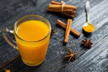 Siyah ahşap bir masada cam bardakta sade baharatlı çay.