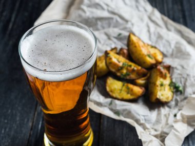 Koyu ahşap arka planda dereotlu patates şeklinde hafif bir bira.