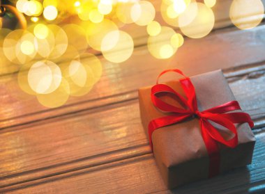 Karanlıktaki ahşap bir masada ampullerle bir hediye.