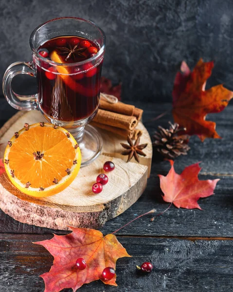 Hot alcoholic winter and autumn drink mulled wine or sangria on a dark table with orange, cinnamon, anise and cranberries