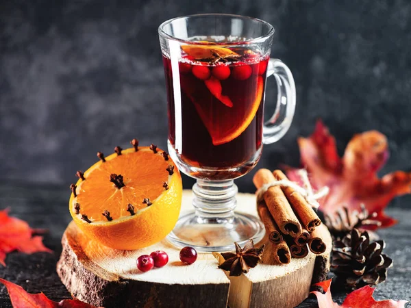 Hot alcoholic winter and autumn drink mulled wine or sangria on a dark table with orange, cinnamon, anise and cranberries