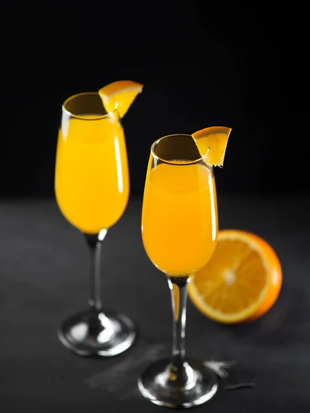 Mimosa drink with orange juice and champagne on a black background