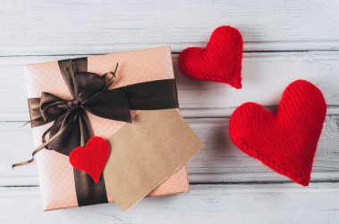 Güzel, büyük, pembe bir hediye kutusu ve ahşap beyaz bir masada örülmüş bir kalp.