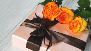 Bayram için güzel bir hediye ve masada bir buket turuncu gül.