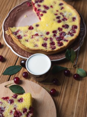 Tahta bir masada, bir kupa sütle ev yapımı vişneli turta.