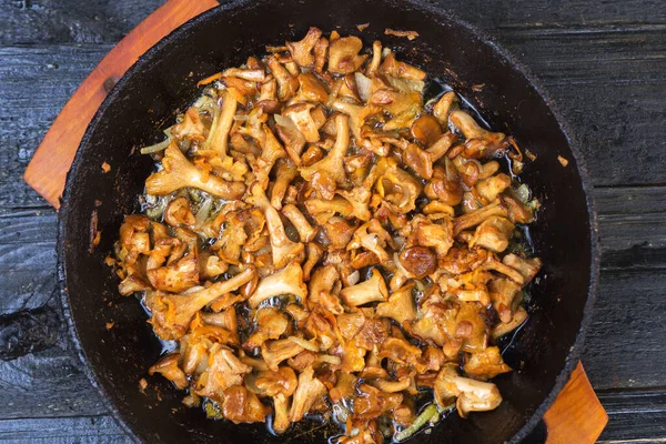 Fried chanterelle mushrooms in a cast iron pan on a rustic black wooden table