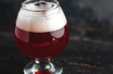 Koyu beton arka planda küçük bir bardakta vişne birası.