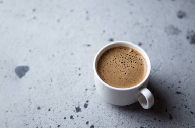 Beyaz espresso kahve fincanı. Gri taş masanın üzerinde.