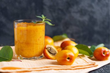 Tahta arka planda bir bardakta kayısı püresi.